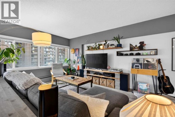 Living room with a sectional sofa, coffee table, television, and record player. - 504, 1209 6 Street Sw, Calgary