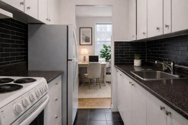 Galley kitchen with white cabinets, black tile backsplash, stainless steel fridge, and stove. - 504 - 1780 Lawrence Avenue E, Toronto