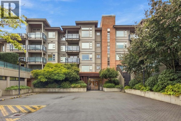 Front exterior of the District Crossing apartment building with balconies and surrounding trees. - 504 1677 Lloyd Avenue, North Vancouver