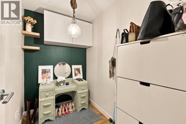 Walk-in closet with green accent wall, vanity, shelves, and white dresser with handbags. - 504 1677 Lloyd Avenue, North Vancouver