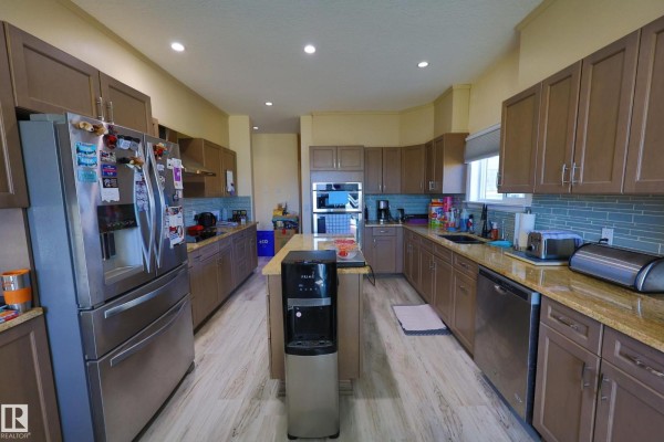 Spacious kitchen with light wood floors, brown cabinets, granite countertops, and stainless steel appliances. - #504 4st 57000 Hwy 44, Alcomdale
