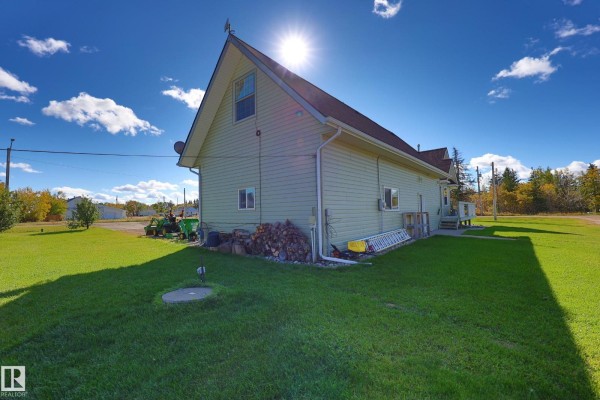 Side view of the house with light green siding, brown roof, and green lawn surrounding the property. - #504 4st 57000 Hwy 44, Alcomdale