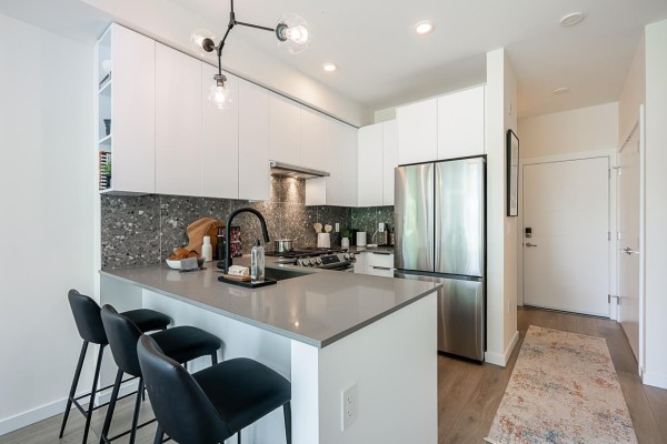 A spacious modern kitchen with dark grey cabinets, white quartz countertops, and stainless steel appliances. - 504 7936 206 Street, Langley