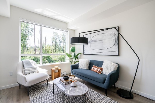 A round wooden dining table with four black chairs is set with place settings in a bright room. - 504 7936 206 Street, Langley
