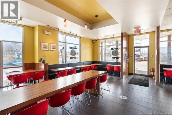 View of commercial interior with booth seating, long wooden table, red chairs, and windows. - 504 Champlain Street Unit# A, Dieppe