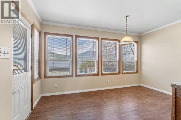 View of a beach and lake with mountains in the distance, featuring a kayak on the sand. - 5041 75 Avenue Ne, Salmon Arm