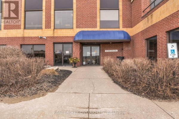 Entrance to the brick apartment building with a blue awning over the doorway. - 505 - 1717 2nd Avenue E, Owen Sound