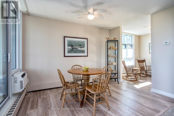 Dining area with a round wooden table and four chairs, adjacent to a living space with rocking chairs. - 505 - 23 Woodlawn Road E, Guelph