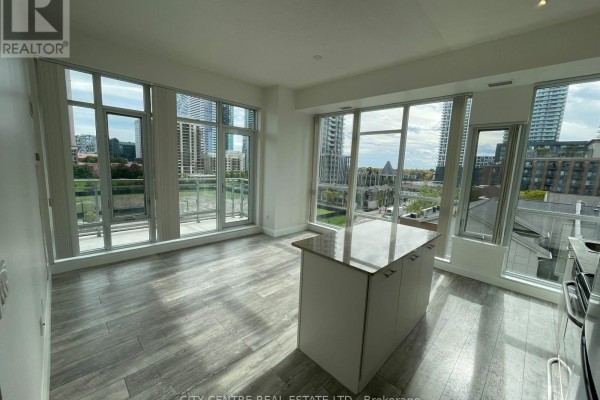 Open concept living area with large windows, light wood floors, and a central island. - 505 - 365 Prince Of Wales Drive, Mississauga