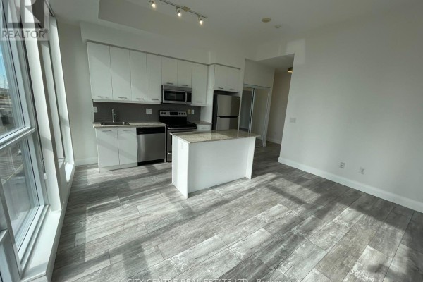 Kitchen and living area with white cabinets, stainless steel appliances, and a granite island. - 505 - 365 Prince Of Wales Drive, Mississauga