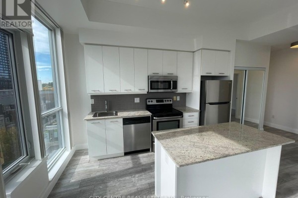 Kitchen featuring white cabinetry, granite countertops, stainless steel appliances, and a central island. - 505 - 365 Prince Of Wales Drive, Mississauga