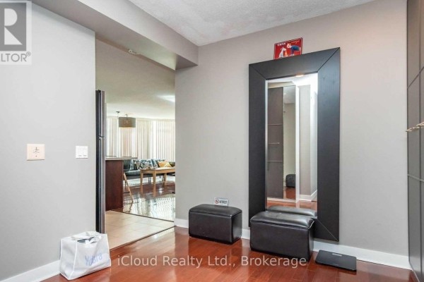 Apartment entryway with a large black framed mirror, two black ottomans, and a coat rack. - 505 - 373 Front Street W, Toronto