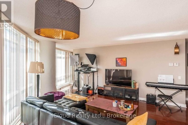 Living room with a black leather sofa, wood floors, large windows, a television, and a keyboard. - 505 - 373 Front Street W, Toronto