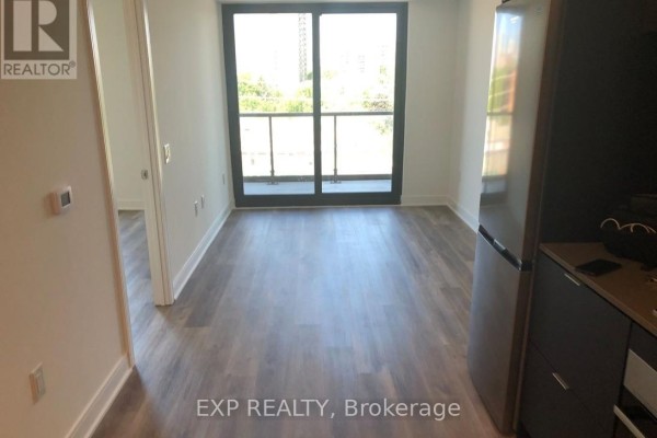 Living area with light wood floors and a sliding glass door leading to a balcony. - 505 - 86 Dundas Street, Mississauga