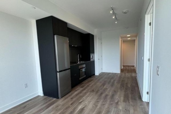Studio apartment kitchen with dark cabinets, stainless steel appliances, and light wood floors. - 505 - 86 Dundas Street, Mississauga