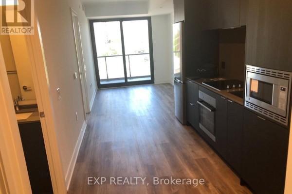 Open concept living space with a kitchen featuring dark cabinetry and stainless steel appliances. - 505 - 86 Dundas Street, Mississauga