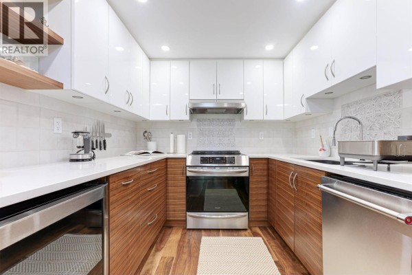 U-shaped kitchen with white and wood cabinetry, stainless steel appliances, and tile backsplash. - 505 1006 Beach Avenue, Vancouver
