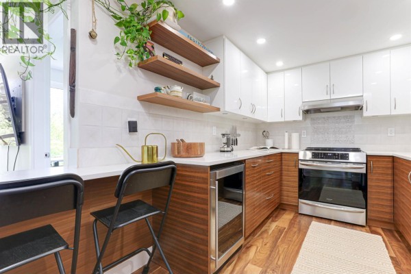 Kitchen counter with two black stools, white countertop, and wood base with stainless steel wine fridge. - 505 1006 Beach Avenue, Vancouver
