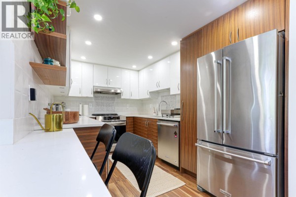 Modern kitchen with stainless steel refrigerator, white and wood cabinets, and wood-look flooring. - 505 1006 Beach Avenue, Vancouver