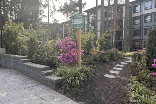 Entrance to Forest Ridge apartment building with trees and landscaping. Private property sign visible. - 505 3535 146a Street, Surrey