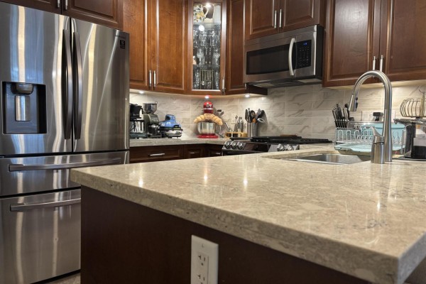 Modern kitchen with stainless steel appliances, granite countertops, and dark wood cabinetry. - 505 3535 146a Street, Surrey