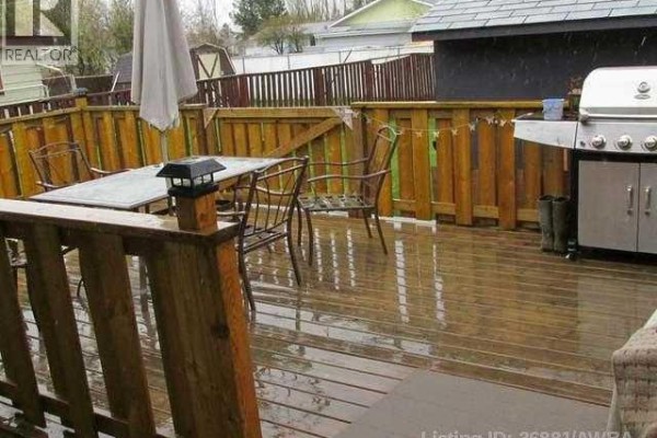 Wooden deck with outdoor dining set, umbrella, and stainless steel barbecue. - 505 5 Avenue, Fox Creek