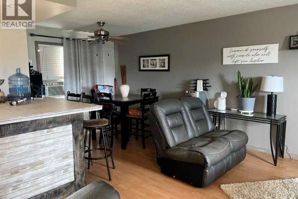 Living room with a leather loveseat, dining table, and console table with a lamp. - 505 5 Avenue, Fox Creek