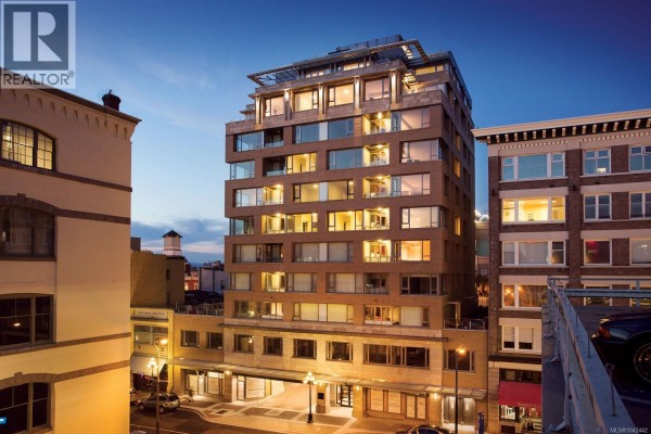 Exterior view of the apartment building at dusk, windows lit from within. - 505 608 Broughton St, Victoria