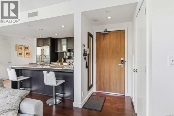Apartment entryway with hardwood floors, a full-length mirror, and a view into the kitchen. - 505 608 Broughton St, Victoria