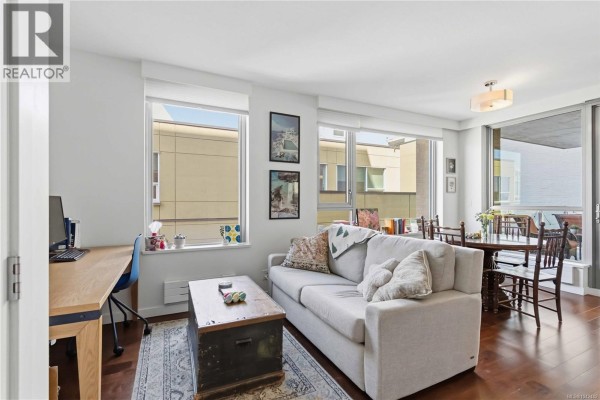 Living and dining area with a sofa, desk, dining table, and large windows overlooking the city. - 505 608 Broughton St, Victoria