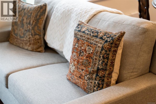 Close-up of a sofa with textured throw pillows and a knitted blanket. - 505 608 Broughton St, Victoria