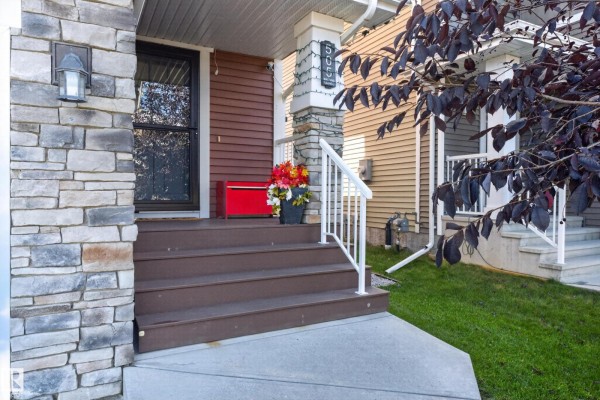 Close-up of duplex front steps with stone accents and a potted floral arrangement. - 505 Ebbers Wy Nw, Edmonton