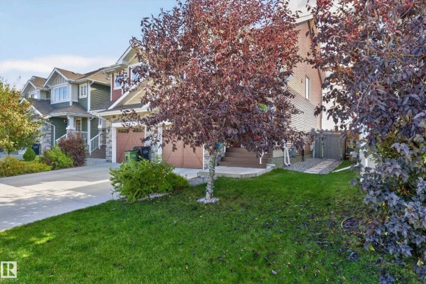 Side view of duplex homes with driveways, garages, and manicured lawns. - 505 Ebbers Wy Nw, Edmonton