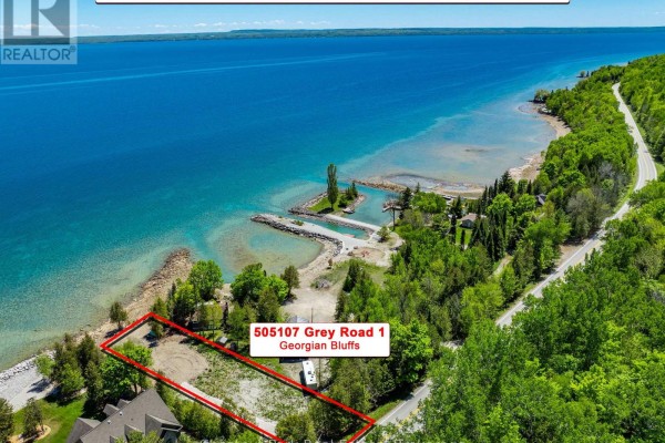 Rocky shoreline with scattered trees and calm blue water stretching to the horizon under a clear sky. - 505107 Grey Road 1, Georgian Bluffs