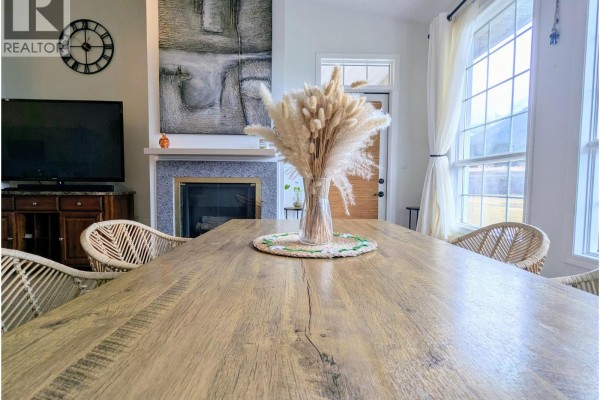 Close-up of dining table with decorative centerpiece, fireplace, and wall art visible in the background. - 5052 Riverview Road Unit# 1013a, Fairmont Hot Springs