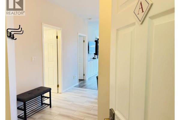 Hallway with bench and coat rack, view into living area and kitchen. - 5052 Riverview Road Unit# 2005 A, Fairmont Hot Springs