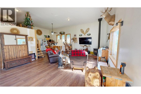 Wooden cabin with a covered porch, situated in a cleared grassy area with surrounding forest. - 5055 95 Highway, Castledale