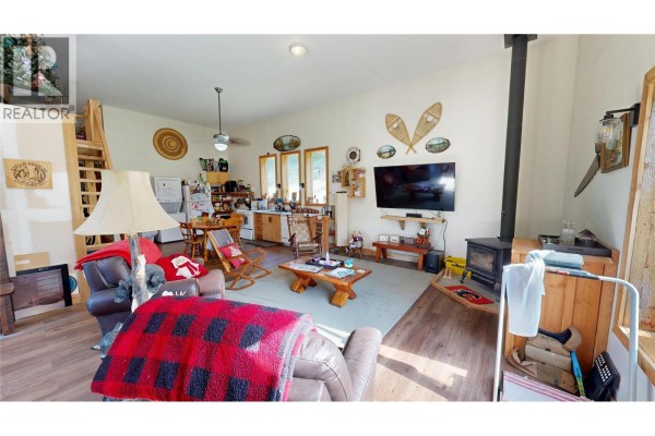 Wooden deck and pergola overlooking a fenced grassy area with trees and mountain views beyond. - 5055 95 Highway, Castledale