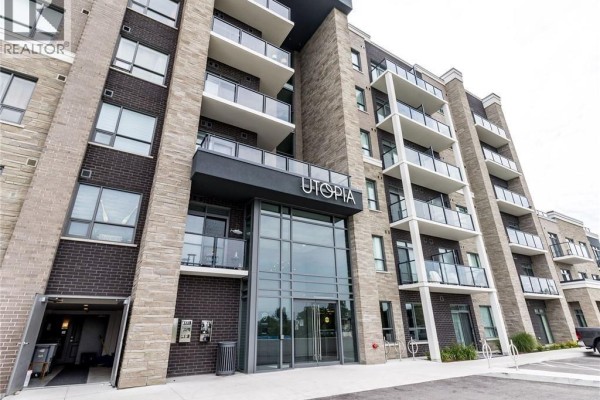 Exterior of a modern apartment building with a glass entrance and balconies on multiple floors. - 5055 Greenlane Street Unit# 337, Beamsville