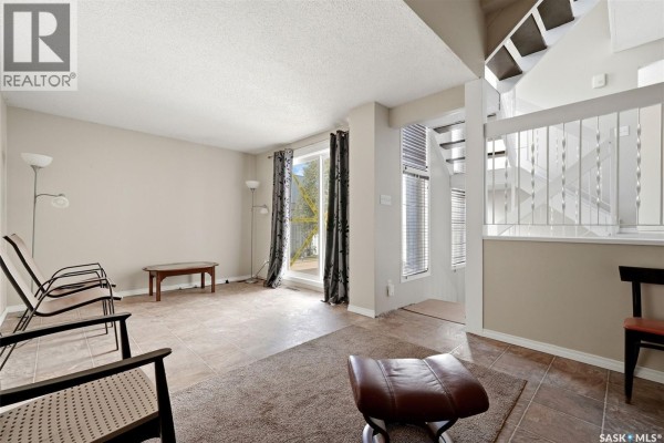 A glass-top table with chrome legs and a gold-framed mirror on a pale beige wall. - 5056 10th Avenue, Regina