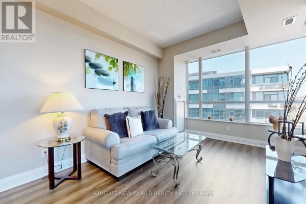 Living room with light grey sofa, glass coffee table, and large windows. - 506 - 1 Hurontario Street, Mississauga