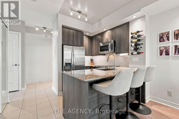 Kitchen island with granite countertop and three bar stools. - 506 - 2756 Old Leslie Street, Toronto