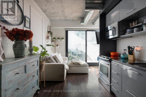 Balcony with hanging chair, outdoor seating, and a small table with a view of apartment buildings. - 506 - 51 Trolley Crescent, Toronto