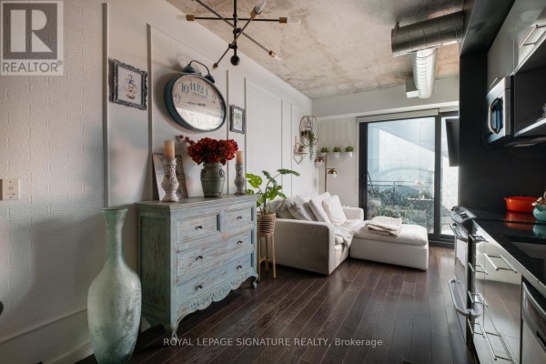 Bedroom with a king-sized bed, grey tufted headboard, and a large white sliding closet door. - 506 - 51 Trolley Crescent, Toronto