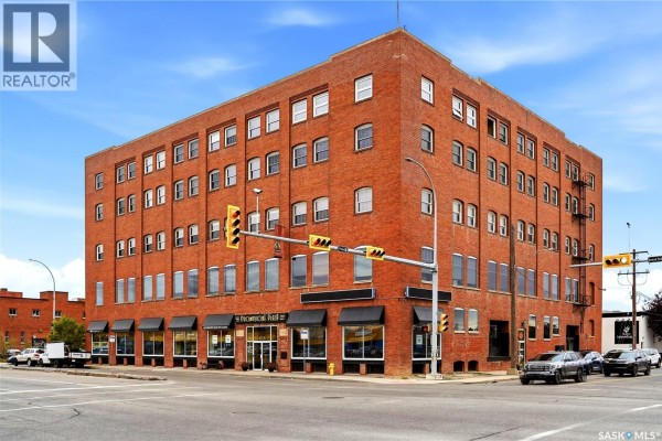 Corner view of a red brick apartment building with black awnings over ground floor windows. - 506 1275 Broad Street, Regina