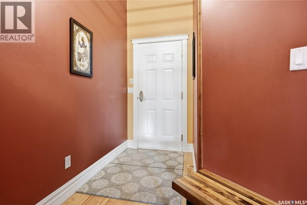 Interior hallway with red walls, a white door, and a patterned rug on light wood floor. - 506 1275 Broad Street, Regina