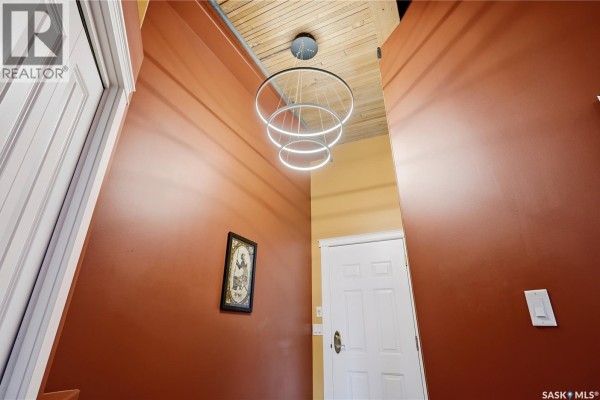 Interior hallway looking up at a circular modern chandelier against a wood-beamed ceiling. - 506 1275 Broad Street, Regina