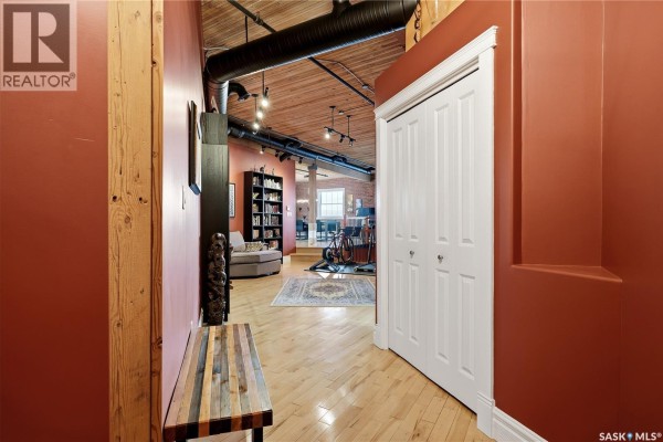 Interior hallway with red walls, wood floor, and view into an open living space. - 506 1275 Broad Street, Regina