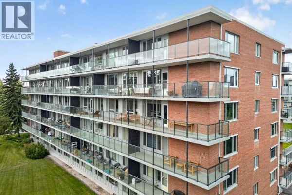 Aerial view of an apartment building showing brick exterior and glass-railed balconies. - 506 507, 3232 Rideau Place Sw, Calgary