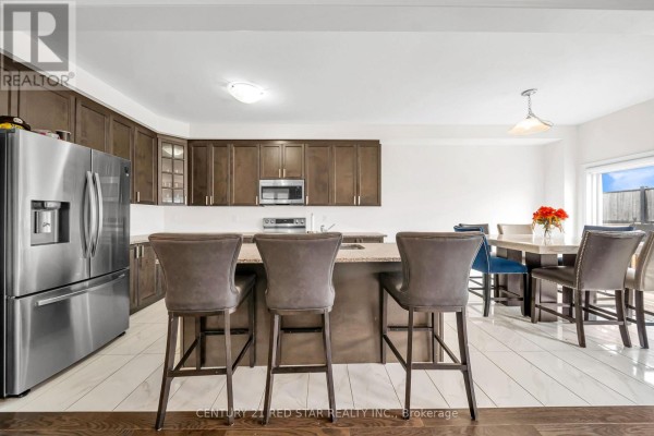Modern kitchen with island, bar stools, stainless steel fridge - 506 Brooks Street Shelburne
